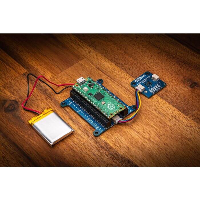 PiicoDev LiPo Expansion Board connected to Raspberry Pi Pico with a LiPo battery on a wooden table.